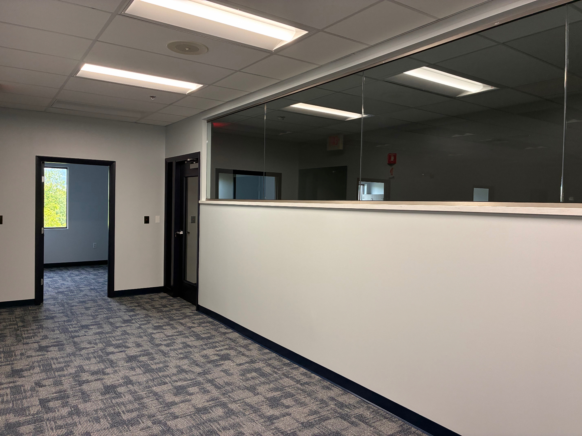 After build-out photo of a finished hallway with completed walls, doors, and lighting